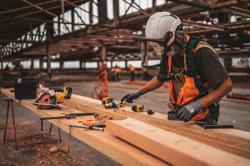 Handwerker bearbeitet Holzbalken, Website fürTischler in Köln